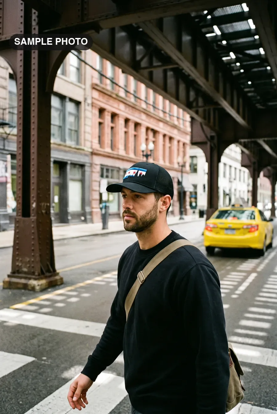 Man in a black Chicago flag cap crossing the street under the L tracks
