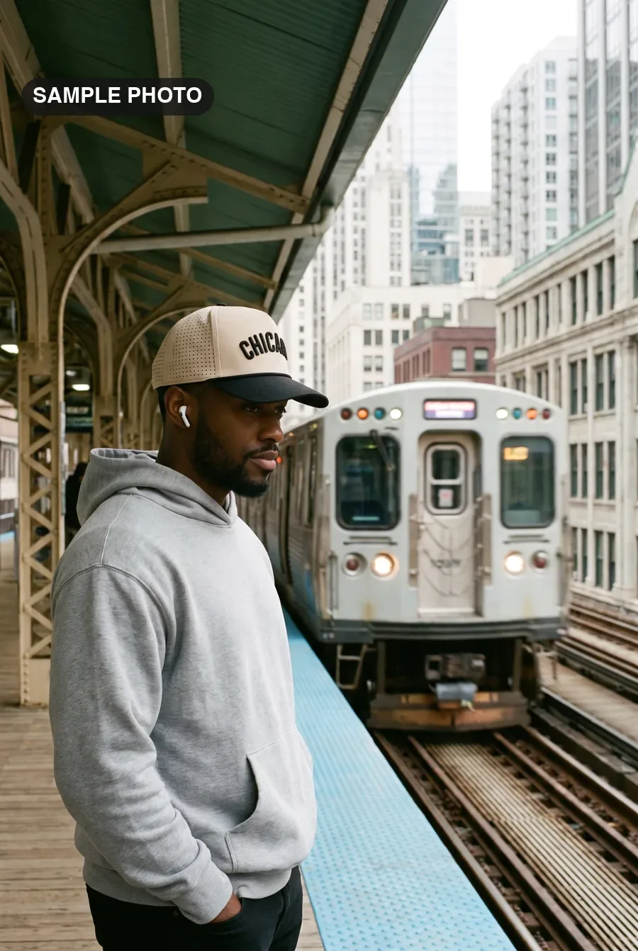 Man in a cream and black Chicago cap waiting on an elevated L platform