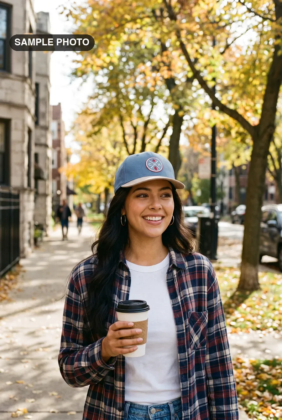 Woman in a blue CH patch cap walking a Logan Square block with coffee